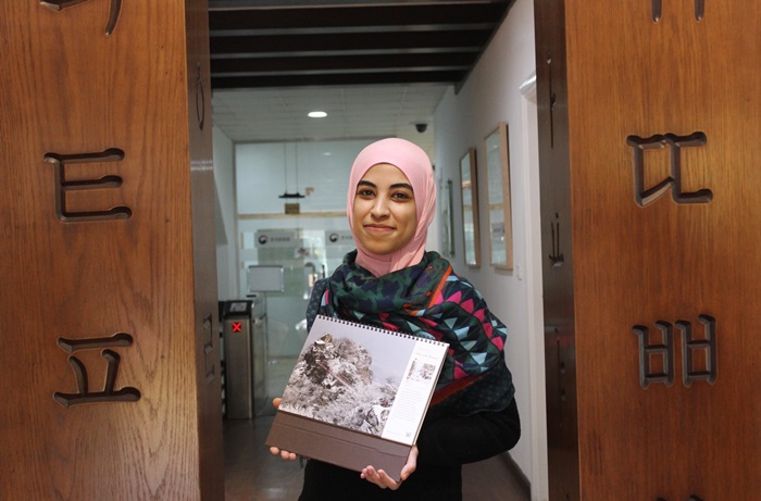  
Korea.net Honorary Reporter Bardise Eldeeb poses for a photo while holding her “Korea Bucket List” calendar’s favorite activity “Hike in the Mountains” at the Korean Cultural Center in Cairo, Egypt. (Esraa Elzeny) 
